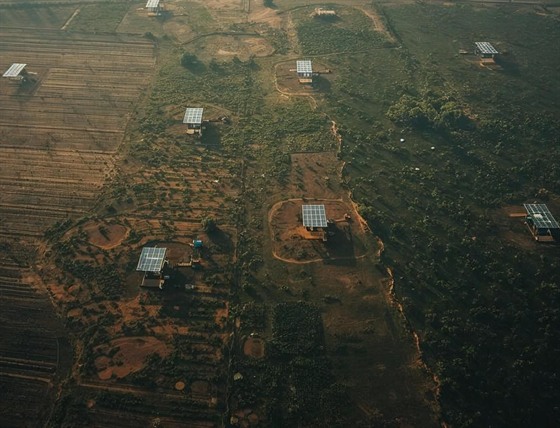 Aerial view of remote structures with solar panel arrays across rural terrain